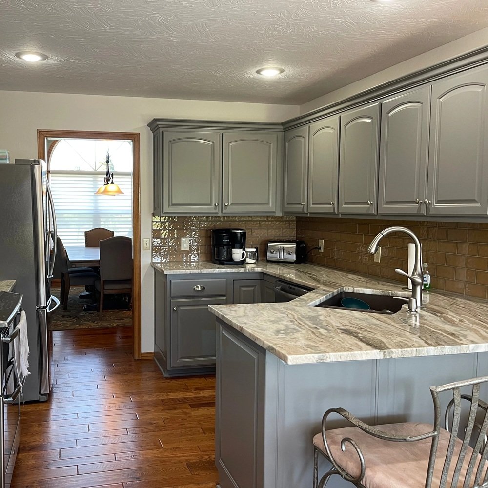 Painter refinishing worn kitchen cabinet doors during an occupied home update