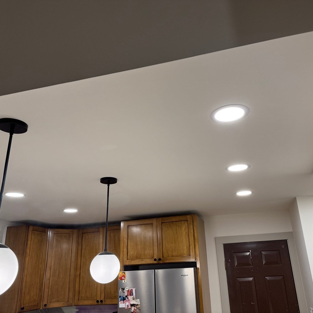 Experienced technician smoothing drywall compound over a repaired ceiling seam