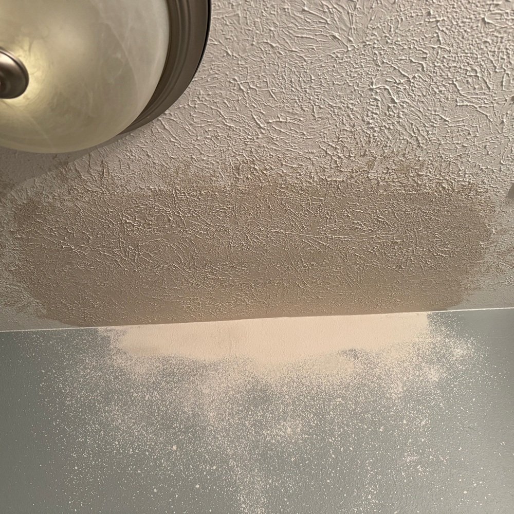 Worker patching a damaged living room wall before repainting begins
